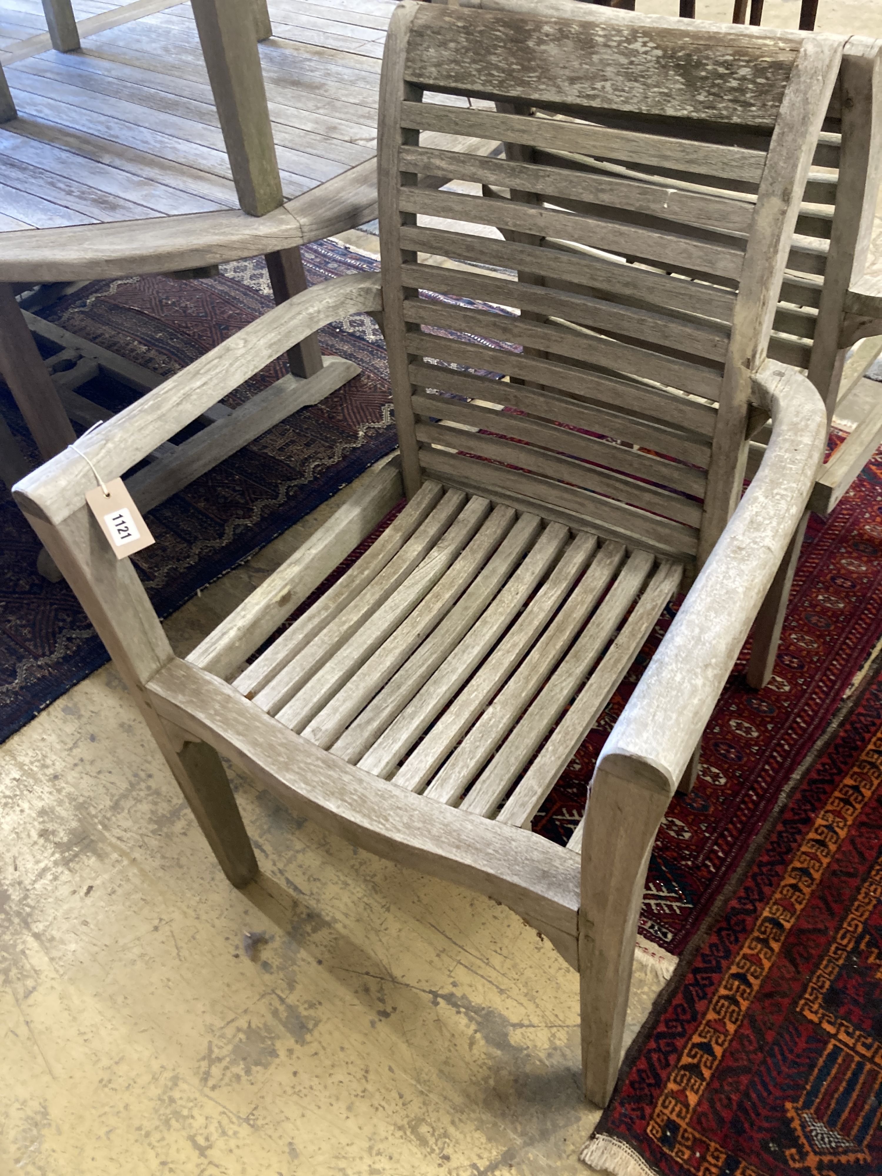A weathered teak extending garden table, length 240cm extended, depth 100cm, height 77cm together with a set of seven weathered teak elbow chairs